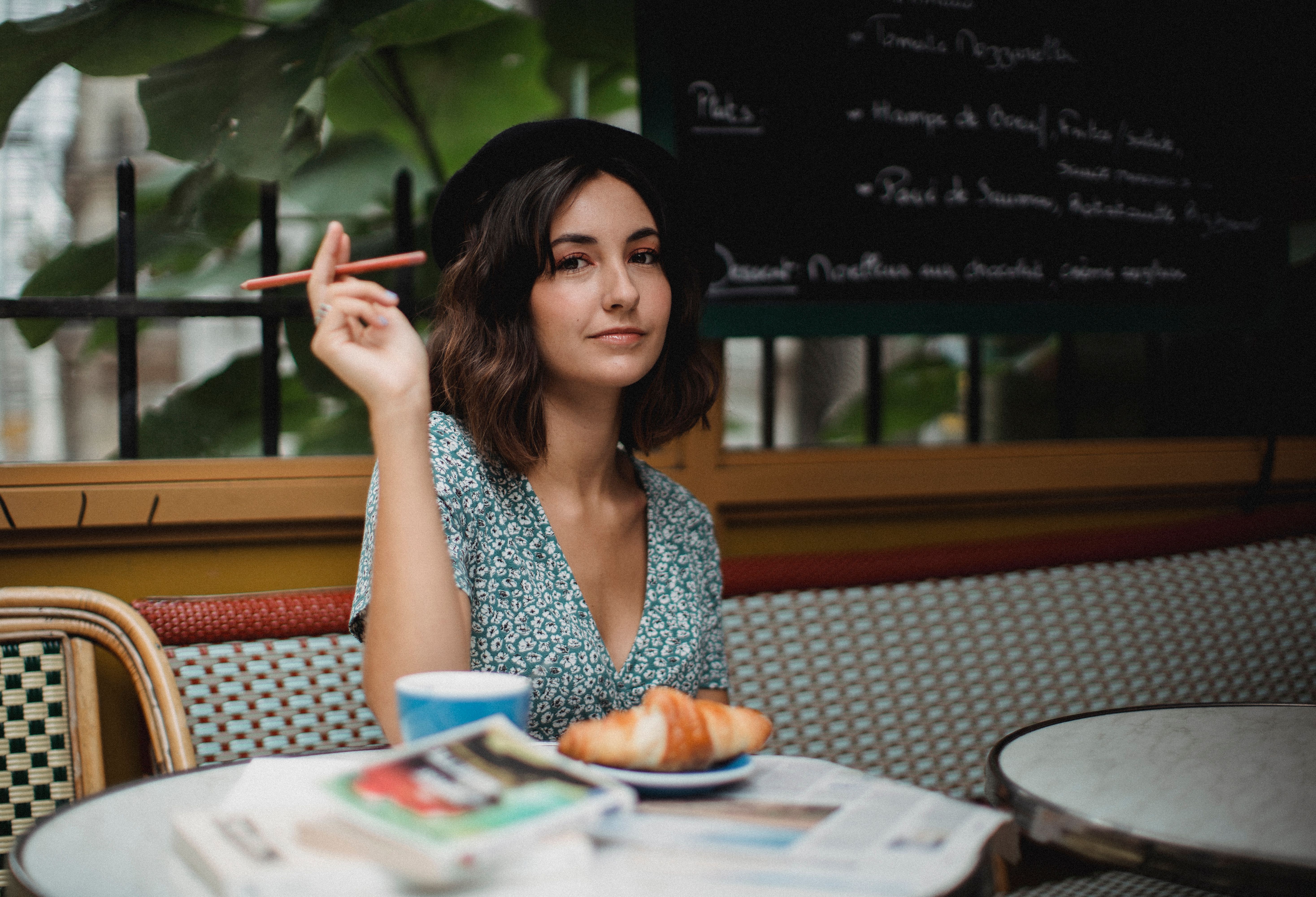 A traveler enjoying coffee and a croissant at an elegant outdoor café, suggesting an easy solo pause during a European city break.